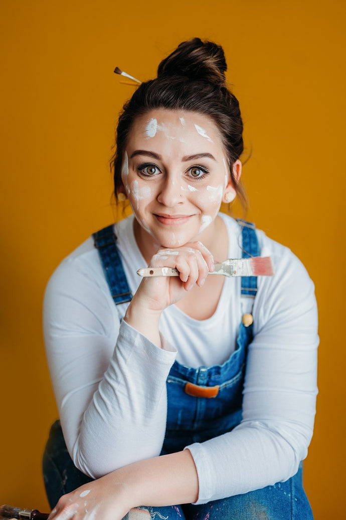 Billie Asmus, Repaint Tray inventor, pictured in overalls holding a paintbrush and with paint splatters on her face